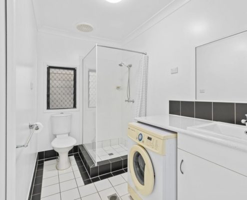 Bathroom showing a shower, toilet, sink and a washing machine