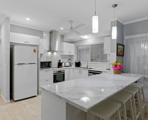Kitchen showing a vast array of appliances as well as a breakfast nook with four stools